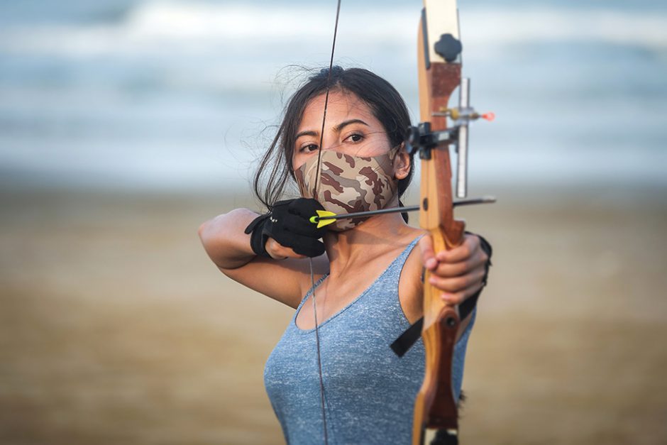 Asian Archery woman with bow shooting on the beach